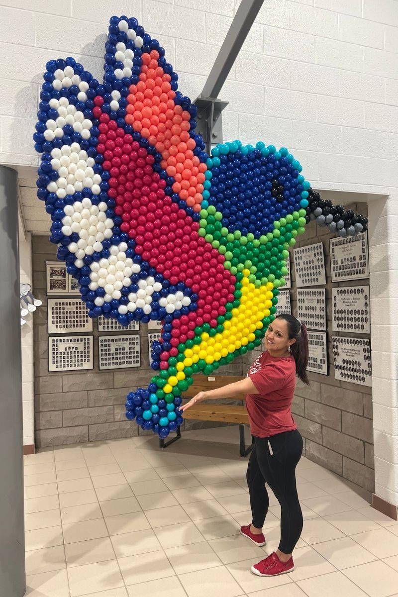 Woman Posing Next to a Huge Colorful Bird Balloon Mosaic | Majestic Balloons | Cambridge, Ontario