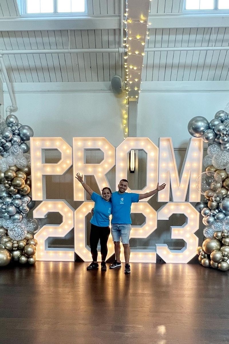 Two People Posing in Front of Marquee Prom 2023 with Two Gold and Silver Balloon Towers | Majestic Balloons | Cambridge, Ontario