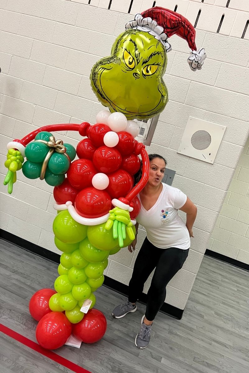 Woman Posing Next to a Grinch Balloon Sculpture | Majestic Balloons | Cambridge, Ontario